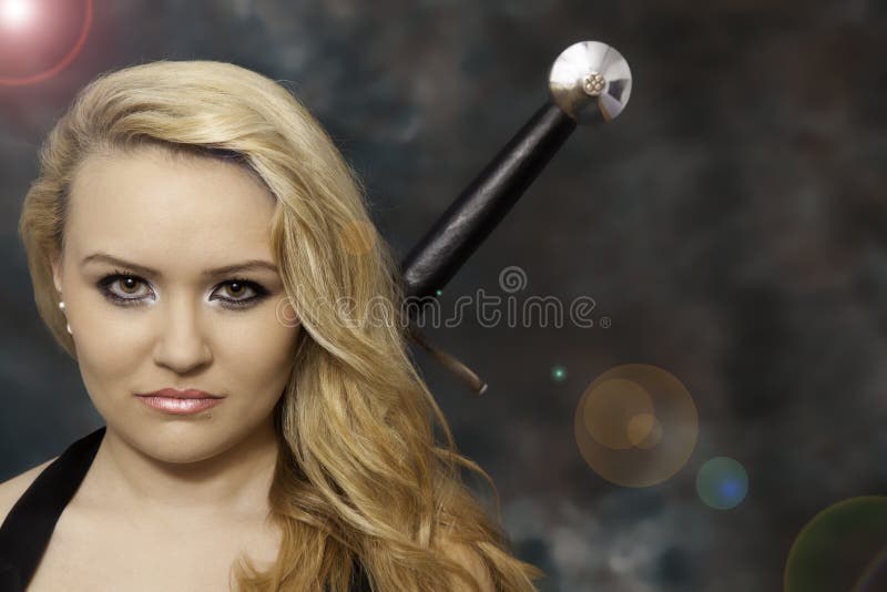 Mulher ou menina loura bonita nova com uma espada atrás da parte traseira imagem de stock royalty free Mulher ou menina loura bonita nova com uma espada atrás da parte traseira imagem de stock royalty free