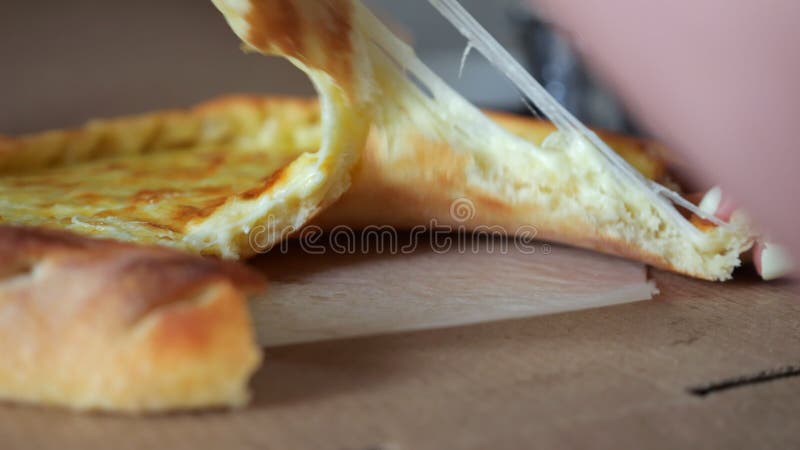 Mulher pega um pedaço de pizza com queijo derretido estirado