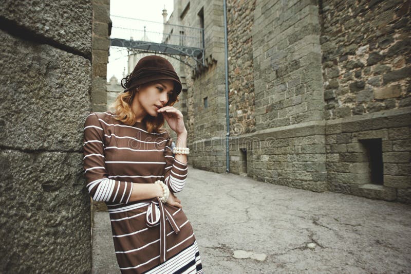 Mulher pensativa que está de inclinação contra a parede do castelo antigo fotos de stock Mulher pensativa que está de inclinação contra a parede do castelo antigo fotos de stock