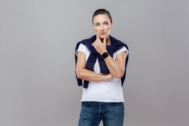 Mulher pensativa que olha ausente quando, toque em seu queixo, AG ereto imagem de stock royalty free Mulher pensativa que olha ausente quando, toque em seu queixo, AG ereto imagem de stock royalty free