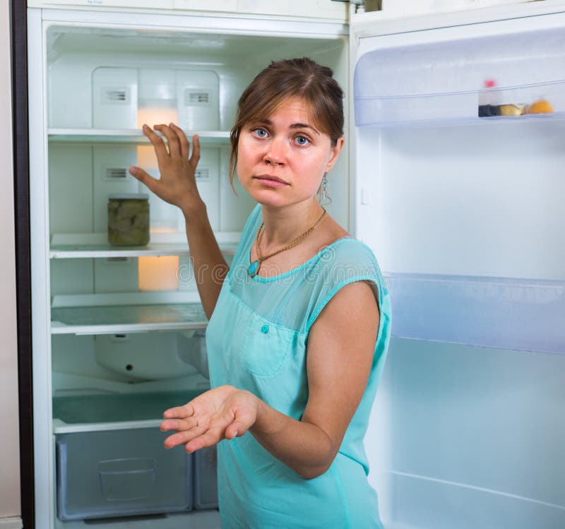 Mulher perto do refrigerador vazio imagens de stock royalty free Mulher perto do refrigerador vazio imagens de stock royalty free