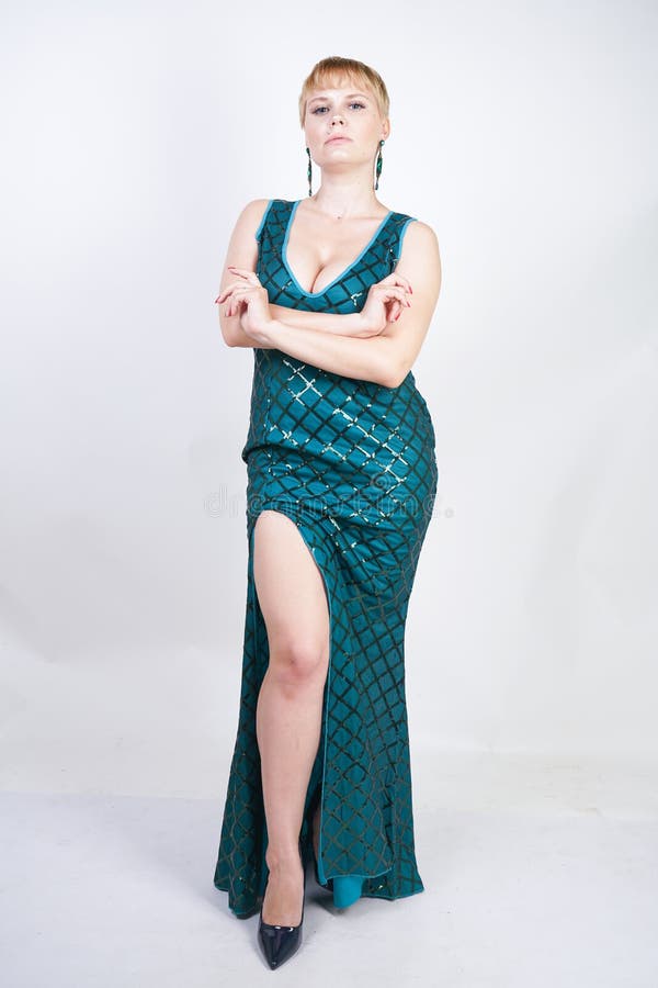 Mulher positiva nova encantador do tamanho com o cabelo louro curto vestido em um vestido longo luxuoso do verde da noite com lan fotos de stock royalty free Mulher positiva nova encantador do tamanho com o cabelo louro curto vestido em um vestido longo luxuoso do verde da noite com lan fotos de stock royalty free