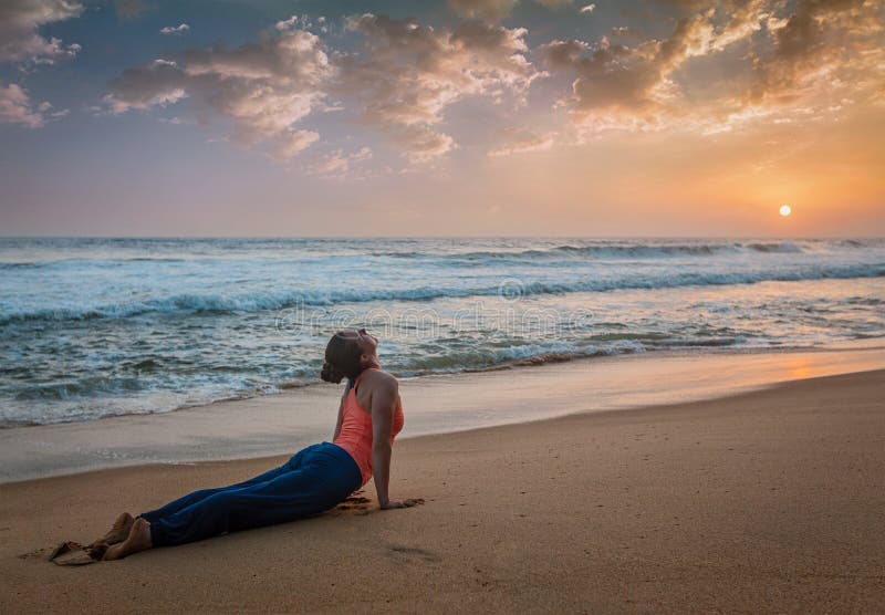 A mulher pratica o asana Urdhva Mukha Svanasana da ioga na praia fotos de stock A mulher pratica o asana Urdhva Mukha Svanasana da ioga na praia fotos de stock