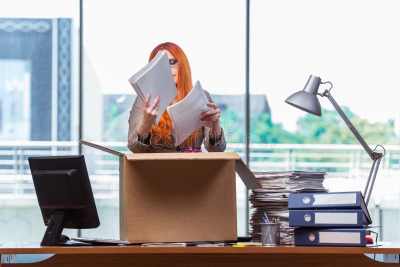 A mulher principal vermelha que move-se para o escritório novo que embala seus pertences foto de stock A mulher principal vermelha que move-se para o escritório novo que embala seus pertences foto de stock