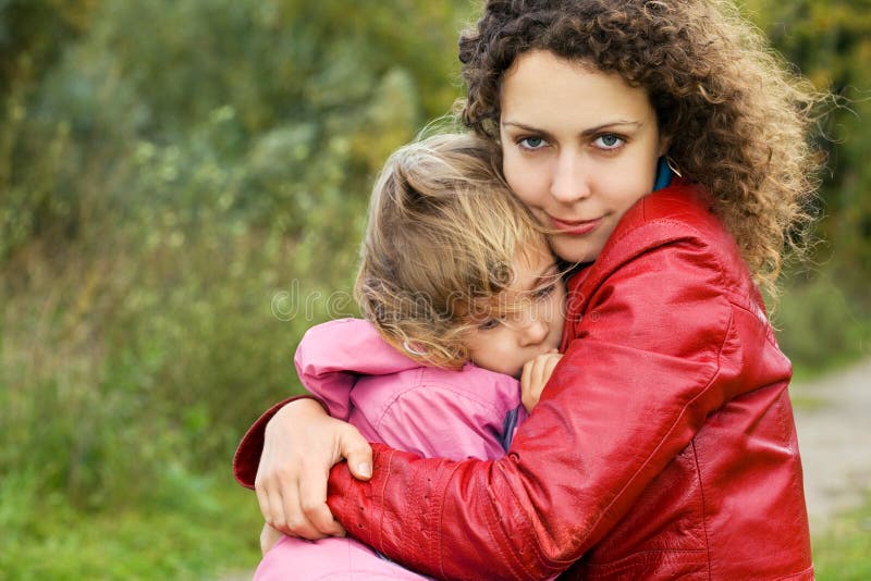 A mulher protege a menina do vento no jardim fotografia de stock royalty free A mulher protege a menina do vento no jardim fotografia de stock royalty free