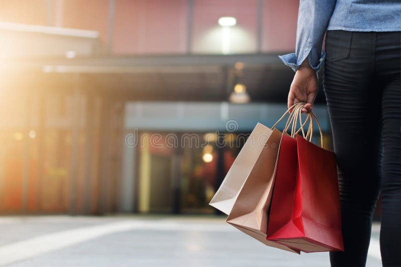 Mulher que anda com os sacos de compras no fundo do shopping imagens de stock Mulher que anda com os sacos de compras no fundo do shopping imagens de stock