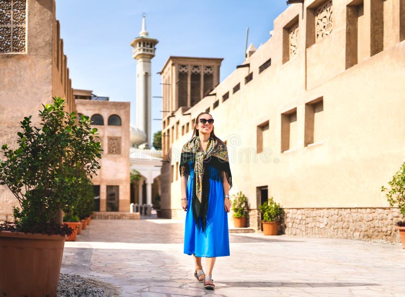 Mulher que anda em Dubai velho, UAE Rua e mesquita árabes tradicionais Turista fêmea na vizinhança histórica de Al Fahidi foto de stock Mulher que anda em Dubai velho, UAE Rua e mesquita árabes tradicionais Turista fêmea na vizinhança histórica de Al Fahidi foto de stock