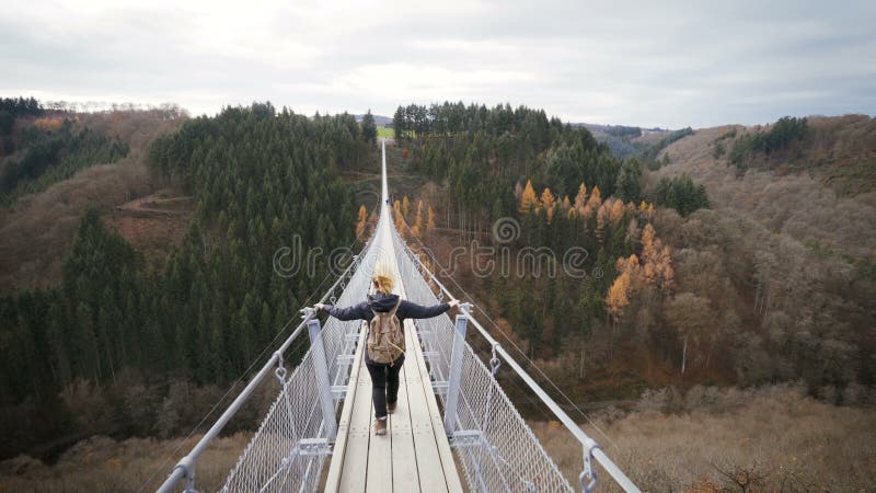 Mulher que anda sobre a ponte de corda da suspensão em Alemanha Conceito do desejo por viajar