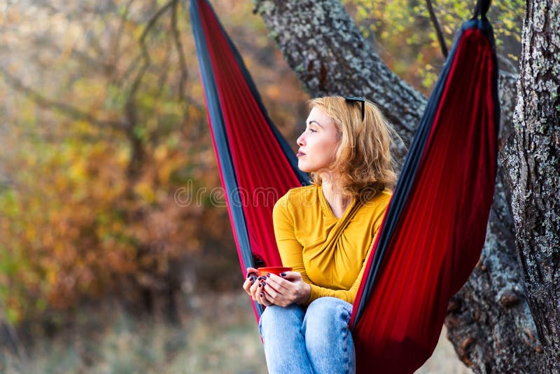 Mulher que aprecia uma xícara de café em uma rede foto de stock Mulher que aprecia uma xícara de café em uma rede foto de stock