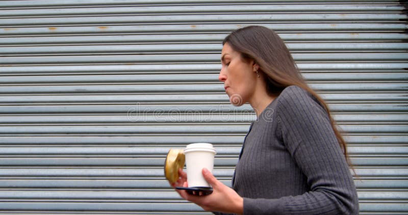 Mulher que come anéis de espuma ao andar na rua 4k