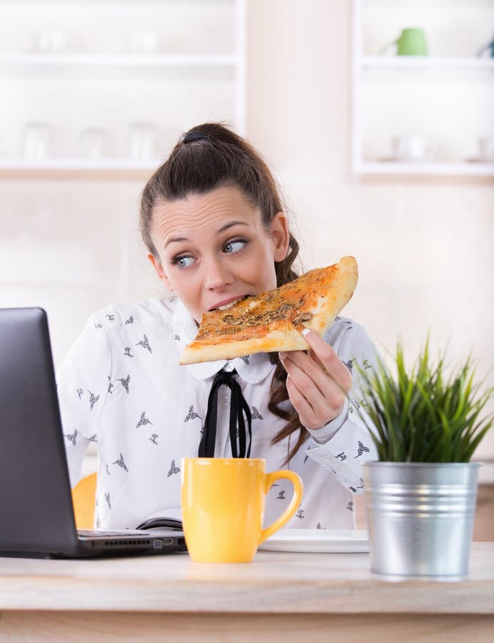Mulher que come o fast food e que trabalha no portátil fotos de stock Mulher que come o fast food e que trabalha no portátil fotos de stock