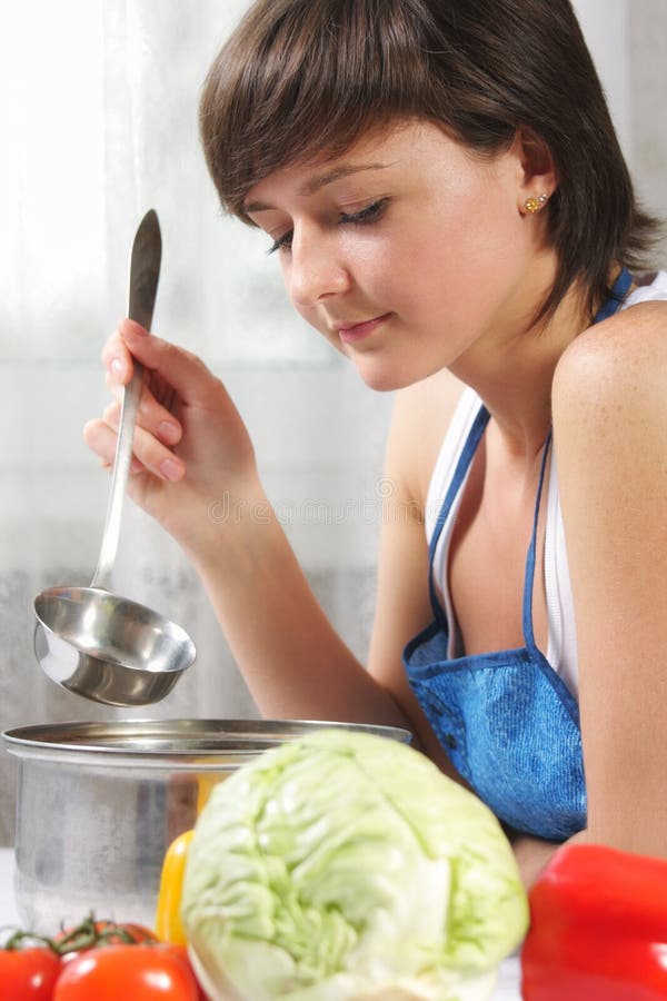 Young brunette woman cooking food at kitchen sideview photo. Young brunette woman cooking food at kitchen sideview photo