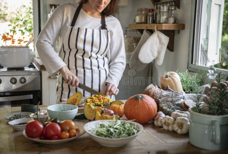 Mulher que desbasta abóboras na cozinha fotografia de stock Mulher que desbasta abóboras na cozinha fotografia de stock