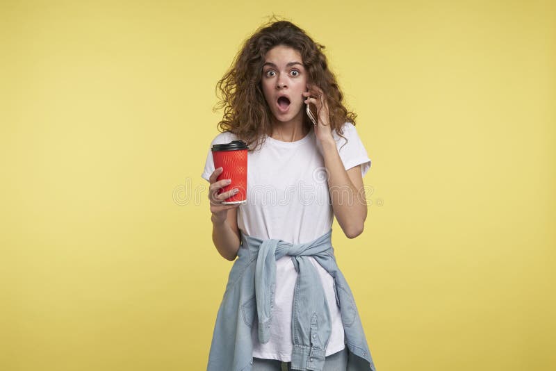 Mulher que fala pelo smartphone e que guarda uma xícara de café, imagem de stock royalty free Mulher que fala pelo smartphone e que guarda uma xícara de café, imagem de stock royalty free