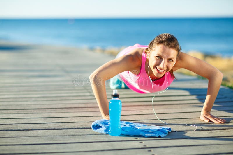 Mulher que faz esportes fora em um trajeto de madeira no mar fotografia de stock Mulher que faz esportes fora em um trajeto de madeira no mar fotografia de stock
