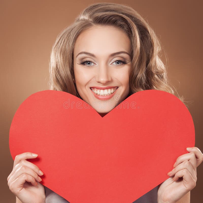 Mulher que guarda o sinal do coração do dia de Valentim com bobina imagem de stock Mulher que guarda o sinal do coração do dia de Valentim com bobina imagem de stock