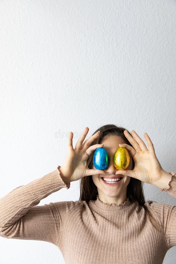 Mulher que guarda ovos da p?scoa azuis e dourados do chocolate na frente de seus olhos fotos de stock Mulher que guarda ovos da p?scoa azuis e dourados do chocolate na frente de seus olhos fotos de stock