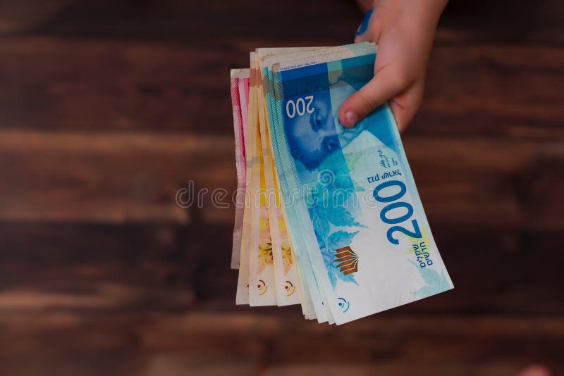 Mulher que guarda um grupo de cédulas novas israelitas do shekel em suas mãos fotos de stock Mulher que guarda um grupo de cédulas novas israelitas do shekel em suas mãos fotos de stock