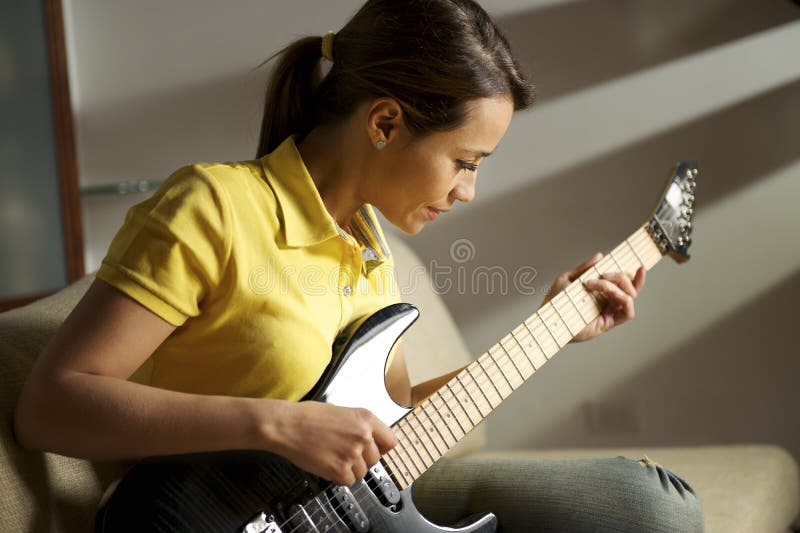 Mulher que joga e que treina com guitarra elétrica em casa imagem de stock Mulher que joga e que treina com guitarra elétrica em casa imagem de stock
