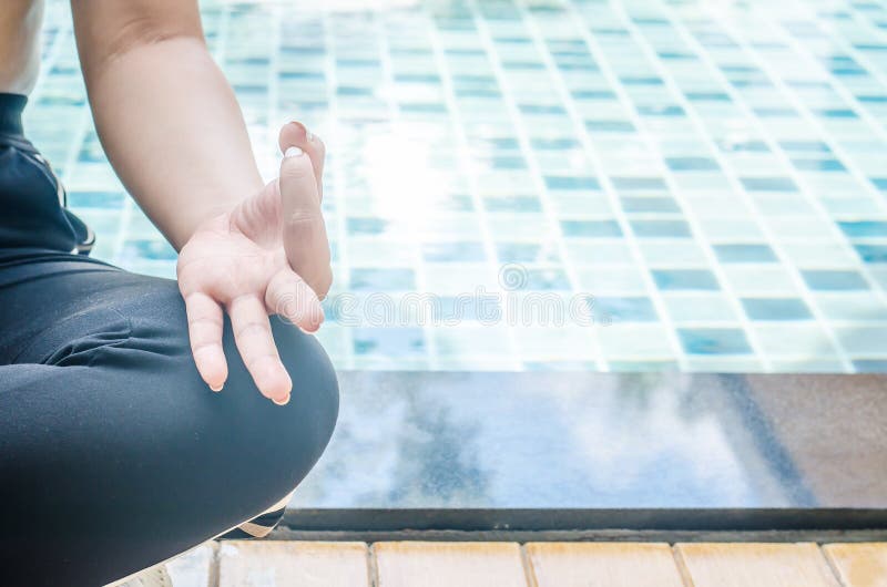Mulher que medita em uma posição da ioga dos lótus na piscina azul imagem de stock Mulher que medita em uma posição da ioga dos lótus na piscina azul imagem de stock