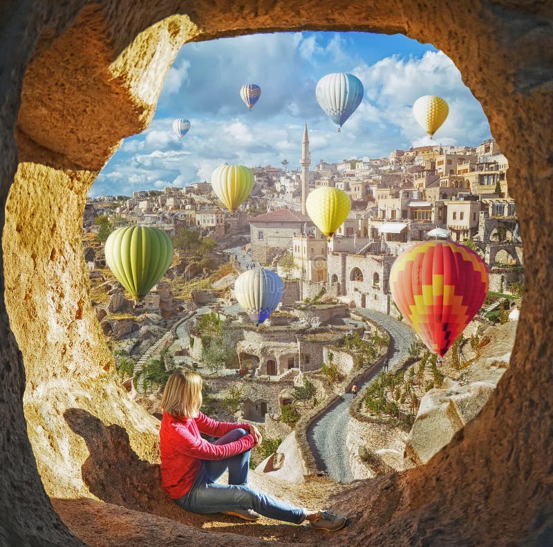 Mulher que olha como os balões de ar quente coloridos que voam sobre o vale em Cappadocia fotografia de stock Mulher que olha como os balões de ar quente coloridos que voam sobre o vale em Cappadocia fotografia de stock