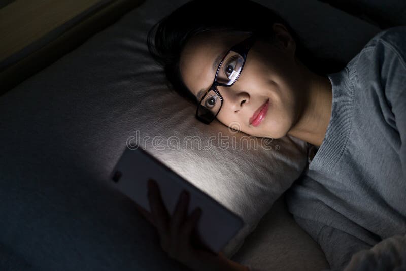 Mulher que olha no telefone celular na cama imagens de stock royalty free Mulher que olha no telefone celular na cama imagens de stock royalty free