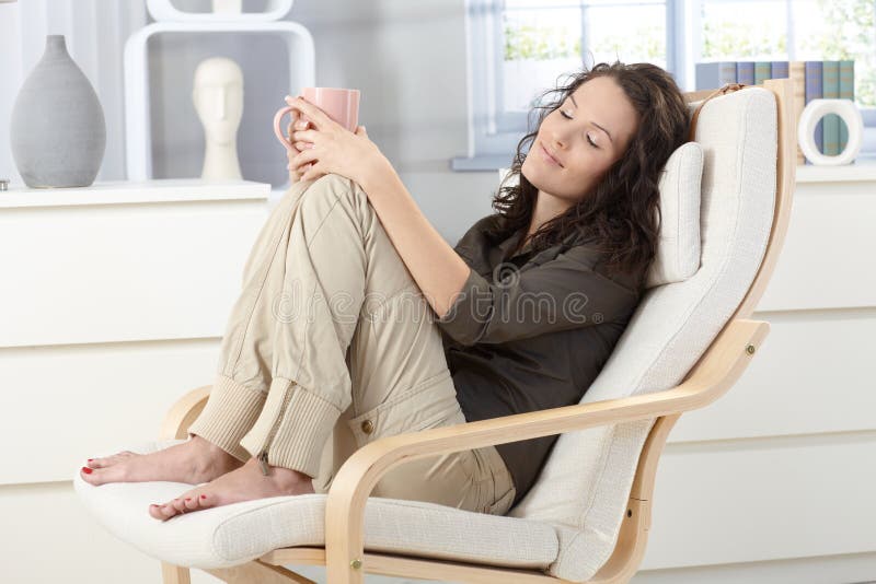 Mulher que relaxa na poltrona fotografia de stock Mulher que relaxa na poltrona fotografia de stock