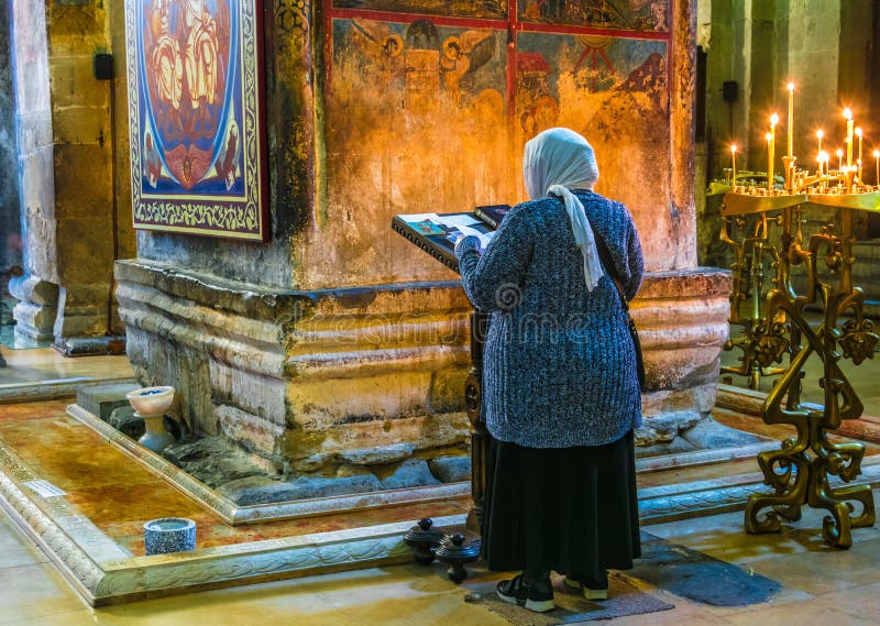 Mulher que reza na catedral de Svetitskhoveli em Mtskheta, Geórgia