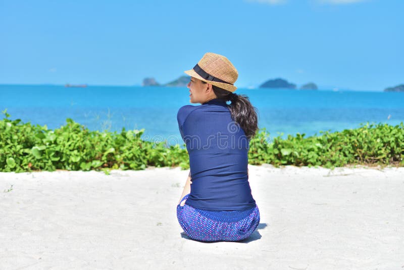 Mulher que senta-se na areia branca no dia ensolarado imagens de stock Mulher que senta-se na areia branca no dia ensolarado imagens de stock