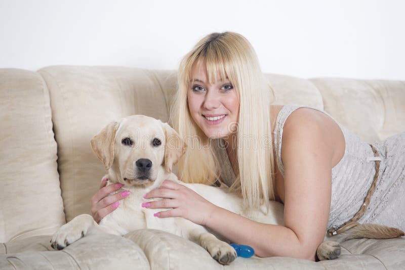 Mulher que senta-se no sofá branco com cachorrinho de Labrador fotos de stock Mulher que senta-se no sofá branco com cachorrinho de Labrador fotos de stock