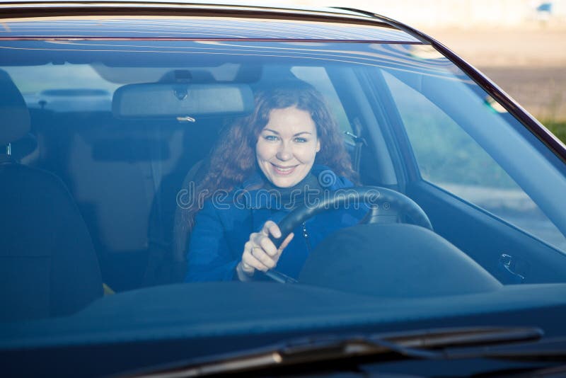 Mulher que sorri através do para-brisa do carro fotos de stock Mulher que sorri através do para-brisa do carro fotos de stock