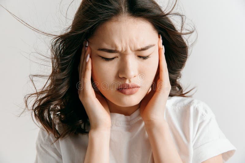 Mulher que tem a dor de cabeça Isolado sobre o fundo cinzento imagem de stock royalty free Mulher que tem a dor de cabeça Isolado sobre o fundo cinzento imagem de stock royalty free