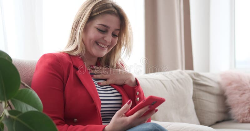 Mulher que tem o divertimento usando o telefone celular em casa