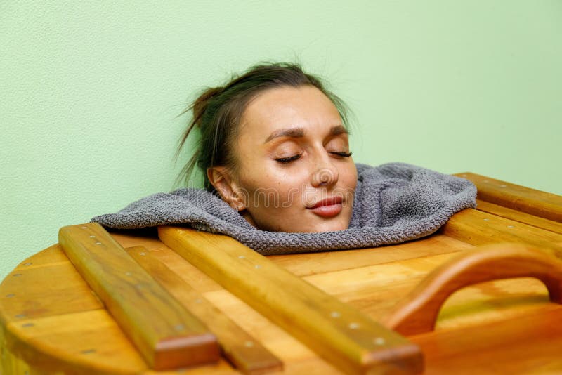Mulher que tem o tratamento dos termas na sauna de madeira do tambor, banheira do cedro foto de stock Mulher que tem o tratamento dos termas na sauna de madeira do tambor, banheira do cedro foto de stock
