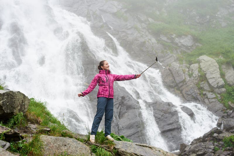 Mulher que toma um selfie na frente da cachoeira grande imagem de stock Mulher que toma um selfie na frente da cachoeira grande imagem de stock