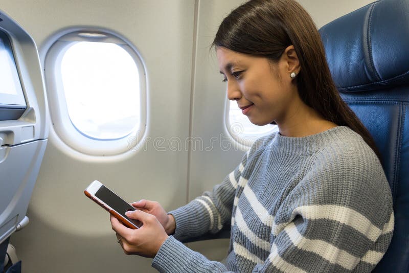 Mulher que usa o telefone celular na cabine plana fotos de stock Mulher que usa o telefone celular na cabine plana fotos de stock