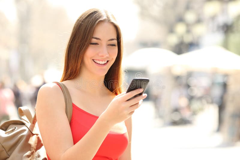 Mulher que usa um telefone esperto na rua no verão Mulher que usa um telefone esperto na rua no verão