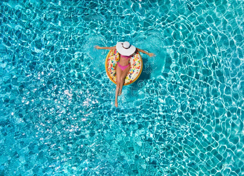 A mulher relaxa em um flutuador em forma de anel sobre a água azul, efervescente da associação fotos de stock A mulher relaxa em um flutuador em forma de anel sobre a água azul, efervescente da associação fotos de stock