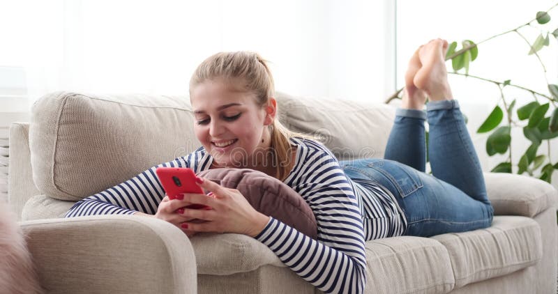 Mulher relaxado que usa o telefone celular em casa