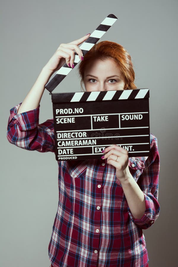 Mulher ruivo bonita que guarda uma válvula do filme, isolada sobre o fundo cinzento imagem de stock Mulher ruivo bonita que guarda uma válvula do filme, isolada sobre o fundo cinzento imagem de stock