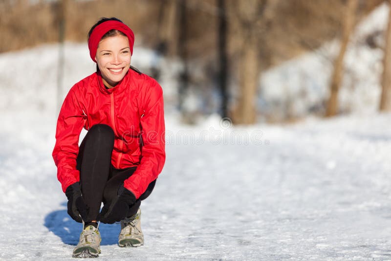 Mulher running do inverno que prepara-se para correr na neve