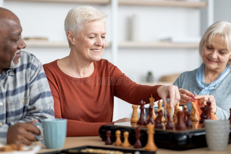 Amigos de xadrez e jogos de tabuleiro na mesa de madeira pensando em  movimento estratégico ou tático em casa grupo sênior de homens jogando e  segurando ou movendo a peça branca para