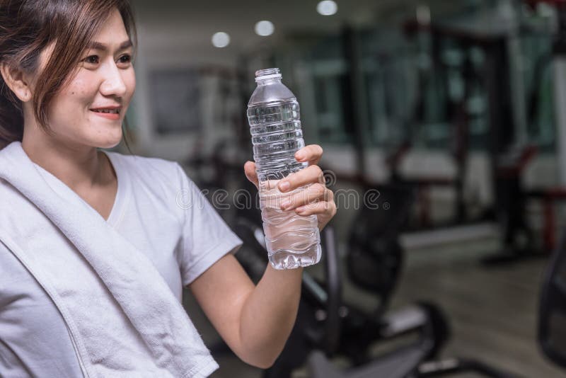 Mulher saudável do esporte que olha a água da bebida imagem de stock Mulher saudável do esporte que olha a água da bebida imagem de stock