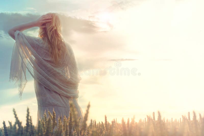 A mulher sonhadora e bonita olha a infinidade enquanto o sol aumenta