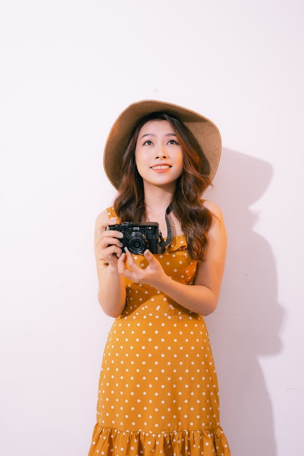 Mulher sorridente e estilosa, posando com câmera retrô em fundo rosa fotos de stock royalty free