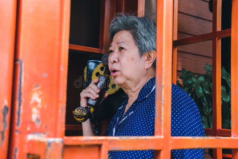 Mulher superior idosa idosa que fala no telefone público do vintage fotografia de stock Mulher superior idosa idosa que fala no telefone público do vintage fotografia de stock
