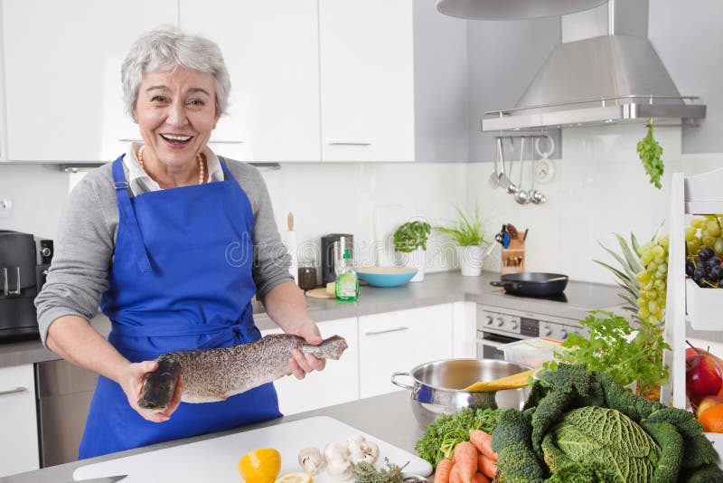 Mulher superior ou mais idosa com cabelo cinzento que cozinha na cozinha - fresca foto de stock Mulher superior ou mais idosa com cabelo cinzento que cozinha na cozinha - fresca foto de stock