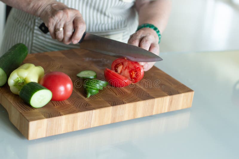 Mulher superior ou mais idosa que cozinha a salada na cozinha Conceito saud?vel do alimento Estilo de vida saud?vel A avó prepara imagem de stock royalty free Mulher superior ou mais idosa que cozinha a salada na cozinha Conceito saud?vel do alimento Estilo de vida saud?vel A avó prepara imagem de stock royalty free