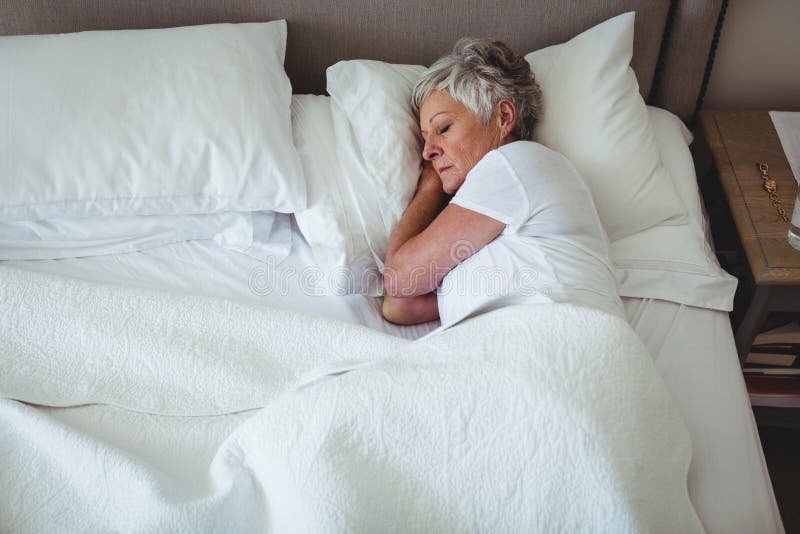 Mulher superior que dorme na cama no quarto imagem de stock royalty free Mulher superior que dorme na cama no quarto imagem de stock royalty free