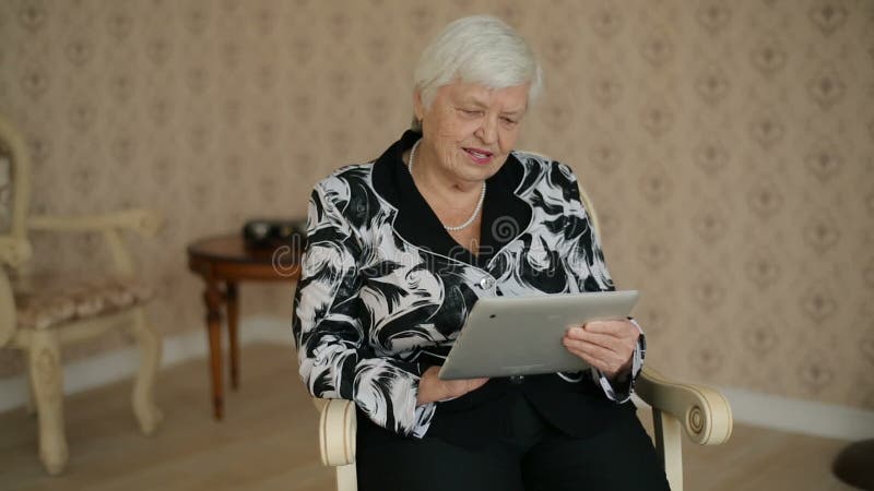 A mulher superior usa o PC da tabuleta video estoque